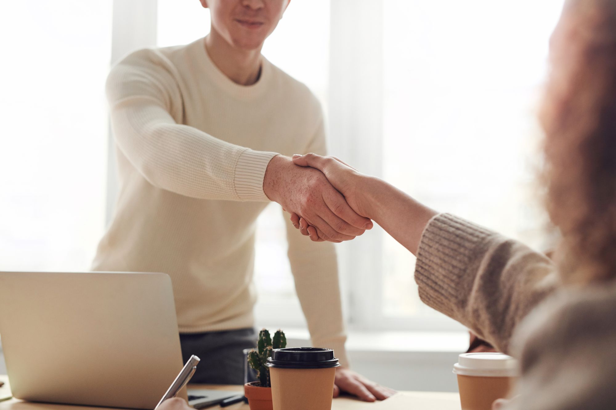 Handshake across a desk during a client meeting